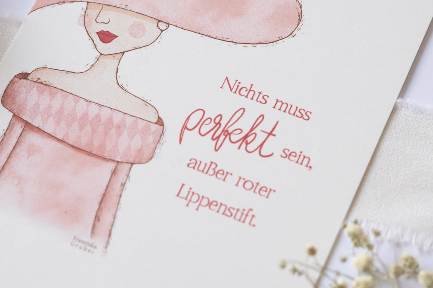 Postkarte mit Illustration einer Frau im Hut und rosa Kleid, Zitat „Nichts muss perfekt sein, außer roter Lippenstift“