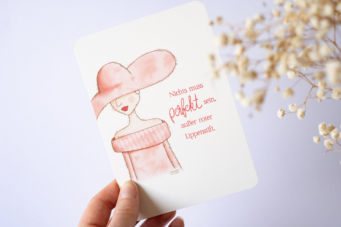 Postkarte mit Illustration einer Frau im Hut und rosa Kleid, Zitat „Nichts muss perfekt sein, außer roter Lippenstift“