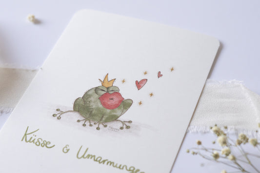 Postkarte mit Froschkönig-Illustration, großem Kussmund und dem Text „Küsse & Umarmungen“ – romantische und fröhliche Karte für Geburtstag, Valentinstag, Hochzeit oder Jahrestag.