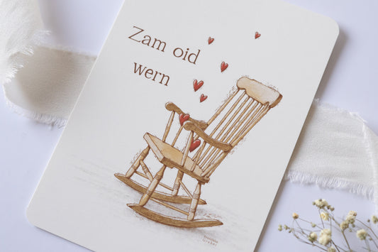 Postkarte „Zam oid wern“ im bayerischen Dialekt mit handgezeichneter Schaukelstuhl-Illustration und roten Herzen – ideal für Hochzeit oder Jahrestag.