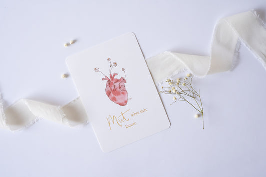 Postkarte mit Illustration eines anatomischen Herzens, aus dem Blumen wachsen, und dem Spruch „Mut lohnt sich. Immer.“ – inspirierende Grußkarte zur Ermutigung