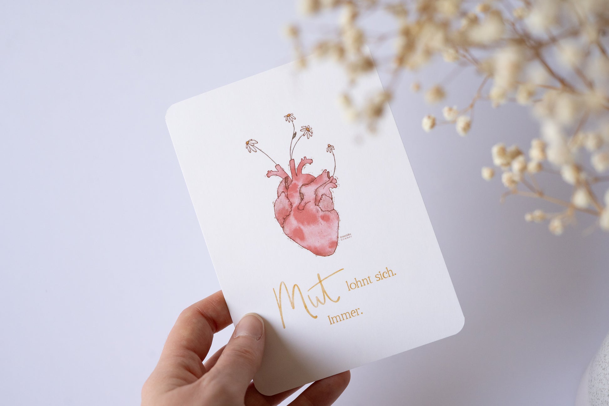 Postkarte mit Illustration eines anatomischen Herzens, aus dem Blumen wachsen, und dem Spruch „Mut lohnt sich. Immer.“ – inspirierende Grußkarte zur Ermutigung
