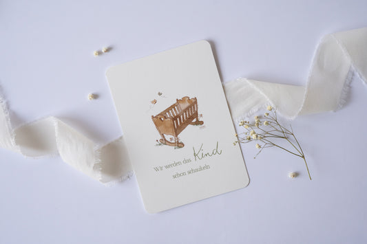 Postkarte mit handgezeichneter Babywiege und dem Spruch „Wir werden das Kind schon schaukeln“ – liebevolle Karte zur Geburt oder Taufe.
