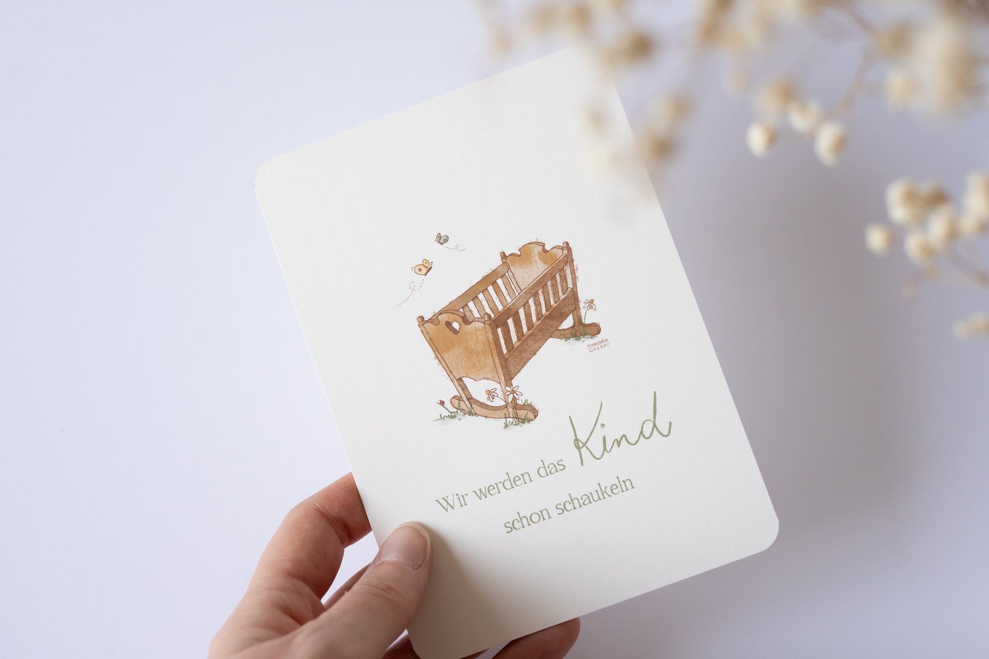 Postkarte mit handgezeichneter Babywiege und dem Spruch „Wir werden das Kind schon schaukeln“ – liebevolle Karte zur Geburt oder Taufe.