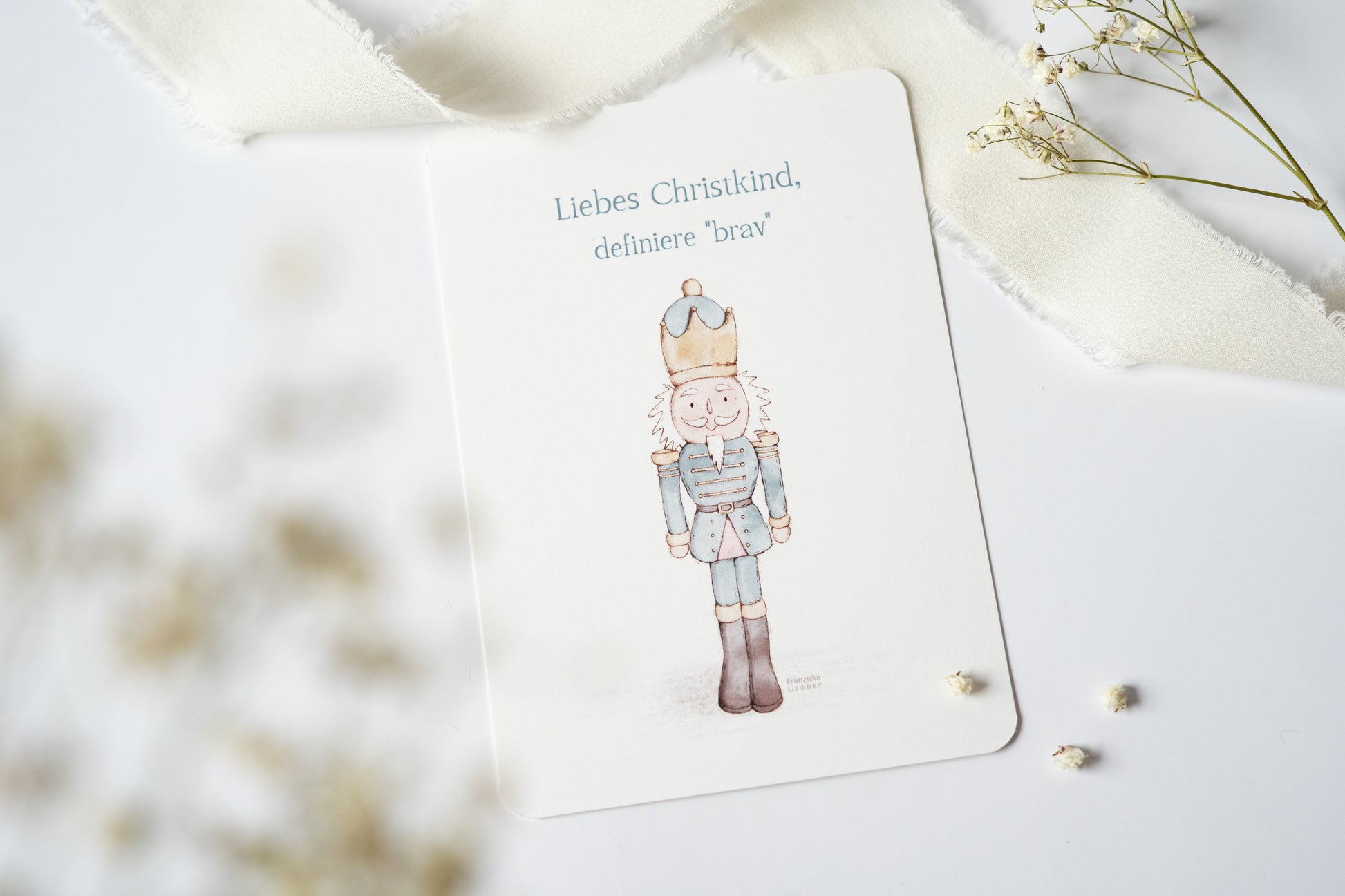 Postkarte „Liebes Christkind, definiere ‚brav‘“ mit liebevoller Illustration eines Nussknackers – humorvolle Weihnachtskarte