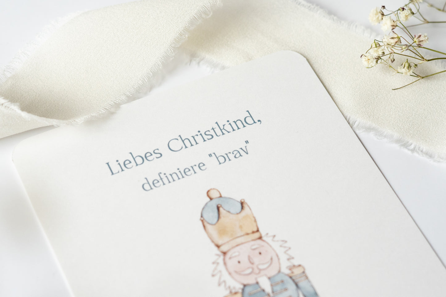 Postkarte „Liebes Christkind, definiere ‚brav‘“ mit liebevoller Illustration eines Nussknackers – humorvolle Weihnachtskarte