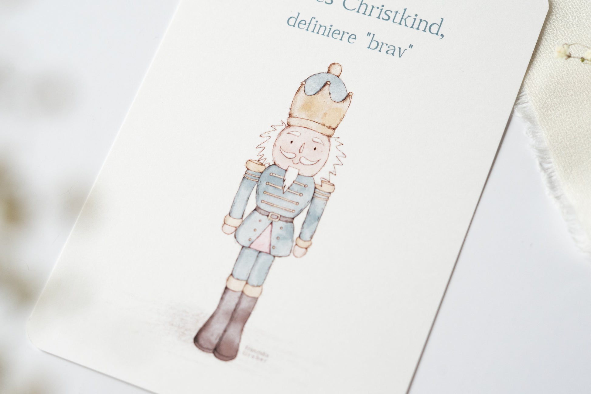 Postkarte „Liebes Christkind, definiere ‚brav‘“ mit liebevoller Illustration eines Nussknackers – humorvolle Weihnachtskarte