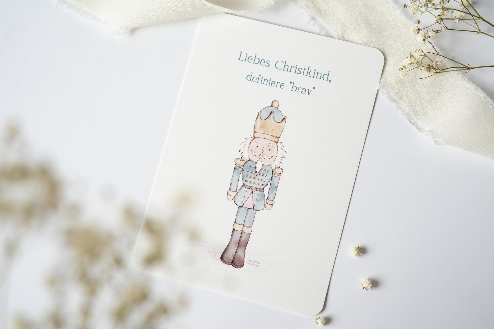 Postkarte „Liebes Christkind, definiere ‚brav‘“ mit liebevoller Illustration eines Nussknackers – humorvolle Weihnachtskarte