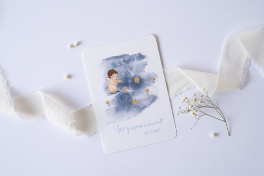 Postkarte mit Engel und goldenen Sternen vor blauem Aquarellhintergrund und dem Spruch „Sterne sind die Vergissmeinnicht der Engel“ – Trauer- und Gedenkkarte.